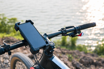 Smartphone and holder attached to the handlebar of a bicycle while parking at the bank of the lake