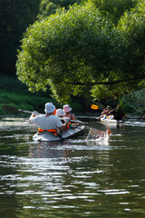 Family with children on rafting trip in Group kayak trip of different ages, adults, elderly. Rowing...