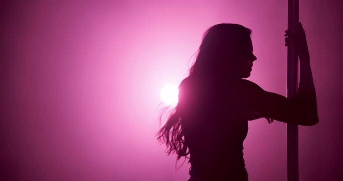 Woman, stage and pole dancer in shadow for dance, exotic performance and seduction in spotlight. Pink neon, aesthetic and performer in silhouette for burlesque, bright light or space in private venue