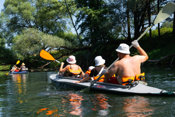 Family with children on rafting trip in Group kayak trip of different ages, adults, elderly. Rowing...