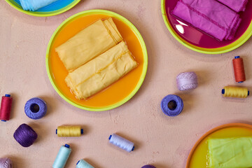 bright background for needlework, dyed colorful fabrics and skeins of thread lying on the table