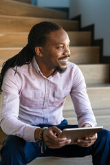 Successful African American businessman reading business graphs and stock charts on digital tablet