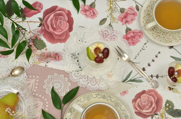 Cups of tea and roses - top view; decorated table for a tea party - plates, desserts, snacks,...