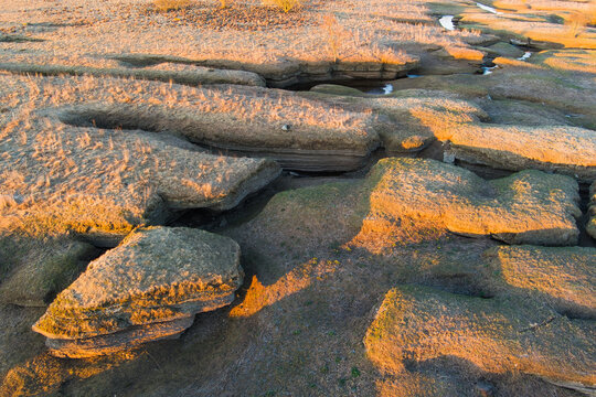 Golden sunlight illuminates the rugged limestone landscape of Kostivere karst zone in Estonia.