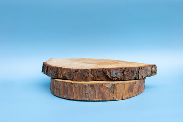 Fototapeta premium Close-up of a two wooden pine log slice with bark on the edges, isolated on a blue background, ideal for rustic or natural décor themes