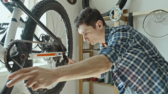 A male bicycle mechanic repairs a mountain bike in a repair shop. The concept of preparation for the new season, repair and maintenance