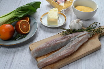 Raw Black Cod Fillet on Cutting Board with Cooking Ingredients in Background