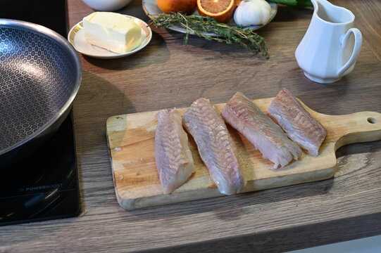 Raw Black Cod Fillet on Cutting Board with Cooking Ingredients in Background