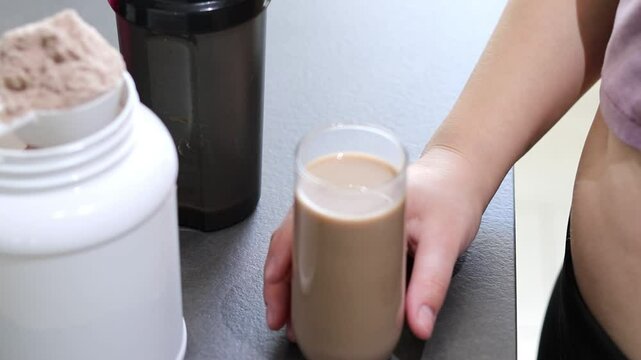 Close up of woman preparing a protein shake in the kitchen. Diet meal replacement for weight loss