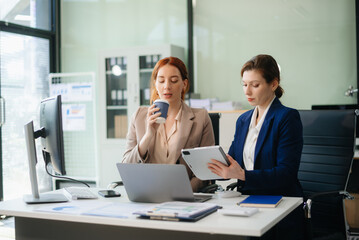 Businesswoman leading team meeting and using tablet and laptop computer with financial