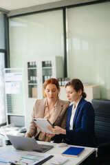 Businesswoman leading team meeting and using tablet and laptop computer with financial