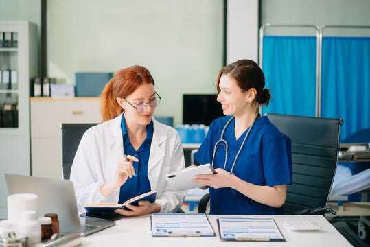 Doctor and nurse team using tablet to review medical results. Diverse healthcare professionals in modern hospital clinic