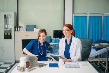 Doctor and nurse team using tablet to review medical results. Diverse healthcare professionals in modern hospital clinic