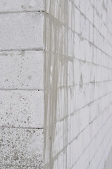 Close-up of a wall made from white aerated concrete blocks. The surface shows texture, seams, and mortar. Part of an unfinished construction under cold weather conditions.