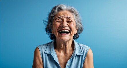 latin Hispanic elderly woman on blue plain bright background happy laughing hysterical looking at camera portrait banner with copy space ad concept marketing