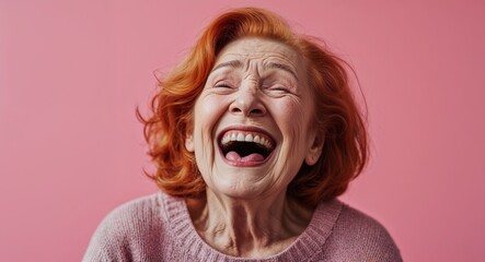 redhead elderly woman on pink plain bright background happy laughing hysterical looking at camera portrait banner with copy space ad concept marketing