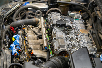 Close-up of modern car engine with valve cover removed during professional automotive repair service. View of cylinder head, fuel injectors, and electrical connectors in vehicle undergoing maintenance
