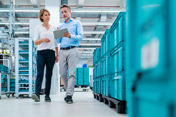 Two professionals discussing in a production hall using a tablet