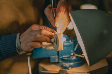 Cremona artisan carefully chisels the pegbox of a violin under focused lighting, hands steady and...