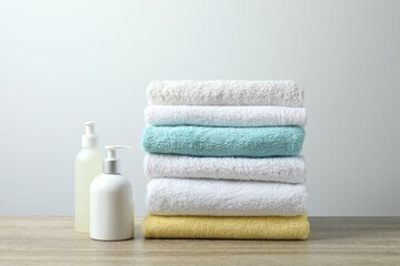 Stack of bath towels with cosmetic bottles on the table