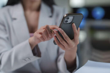 Businesswoman browsing on a smartphone with a stylus pen in a modern office, engaging with...