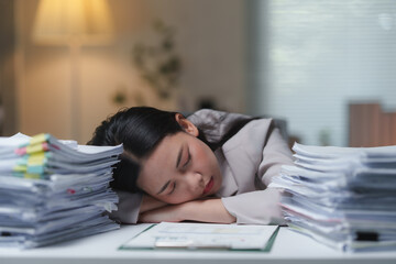 Young office worker sleeping at her desk, surrounded by towering piles of paperwork, struggling with chronic fatigue and the pressures of late-night deadlines in a demanding corporate environment