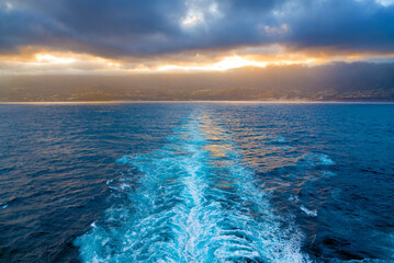 Wake of the ship moving away from the shore at sunset