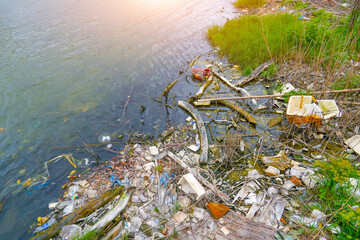 Garbage dumping at mouth river. Waste and plastic debris clutter the water surface near riverbanks,...