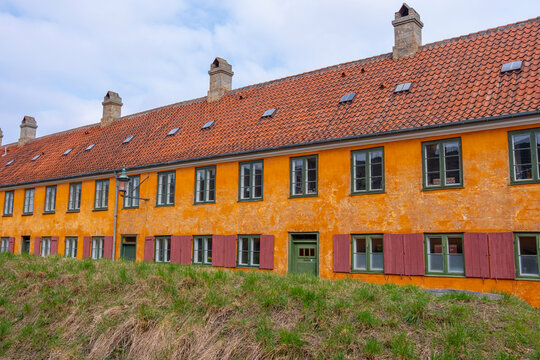 Traditional row houses in Nyboder, Copenhagen, with ochre walls, tiled roofs and aligned windows forming a linear urban rhythm.
