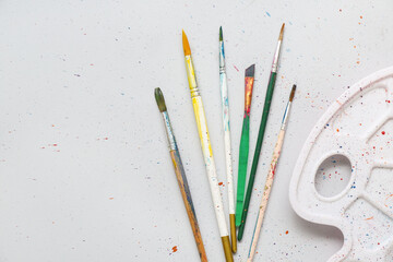 Artist's brushes with paints and palette on grey background