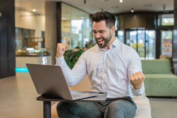 Caucasian bearded businessman working on laptop shocked by sudden victory, game winning lottery...