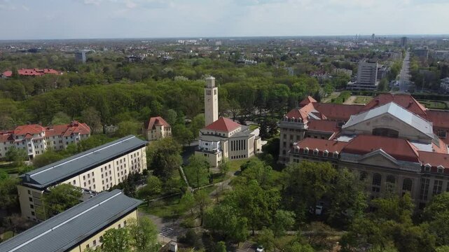 Aerial drone view of Debrecen, Hungary, University of Debrecen, showcasing the city's mix of historic and modern architecture. Campus, church, clocktower surrounded by green trees and urban rooftops.