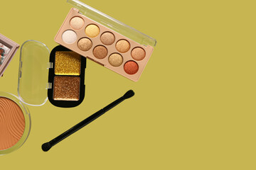 Beautiful palettes of eyeshadows with powder and brush on green background
