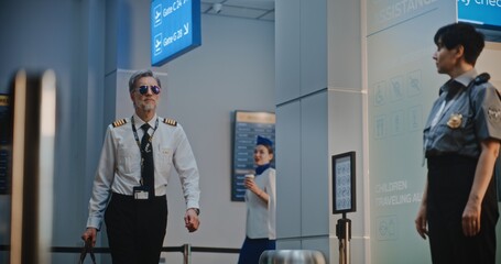 Flight Crew in Airport Terminal: Airline Captain and Two Beautiful Stewardesses in Uniforms Walking...