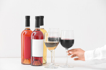 Female hand with glasses of different exquisite wine on light background