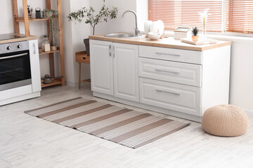 Interior of light kitchen with white counters and striped carpet