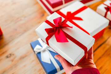  Wrapped Gifts with Ribbons .Person Holding a Wrapped Gift with Red Ribbon.Hand Holding Blue Gift...
