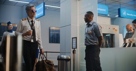 Flight Crew in Airport Terminal: Mature Airline Pilot and Two Beautiful Flight Attendants in...