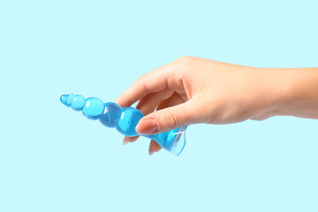 Female hand with anal plug on blue background