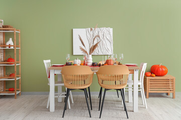 Autumn table setting with pumpkins, dry leaves and burning candles in dining room