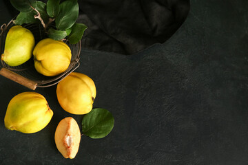 Basket with sweet ripe quinces and leaves on black background