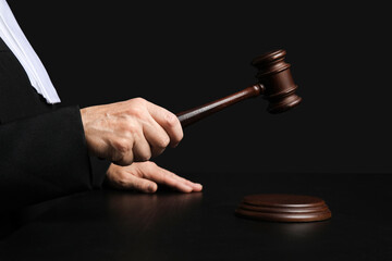 Female judge with gavel at table on black background