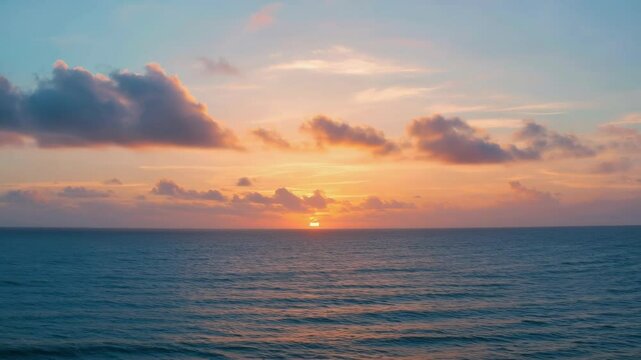 Peaceful sunset over the ocean with clouds in the sky, creating a beautiful horizon line. The image captures the tranquility of the scene.