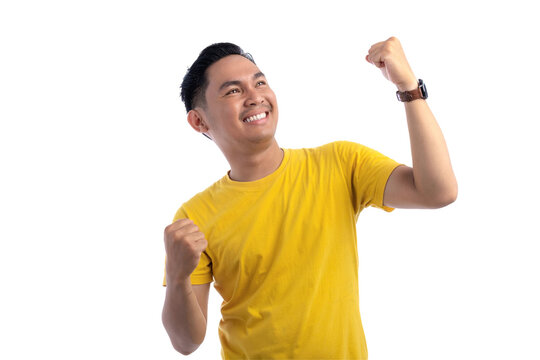 Portrait of excited handsome Asian man raising hands, celebrating good luck, gesturing victory isolated on transparent background