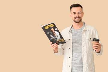 Handsome man with coffee cup reading magazine on beige background