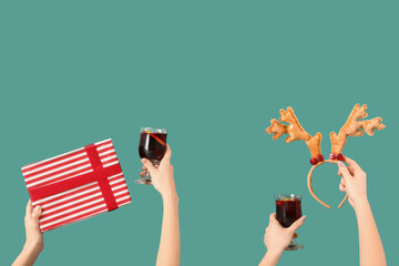 Female hands with glasses of warm mulled wine and Christmas decor on green background