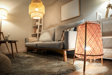 Interior of modern living room with grey sofa and glowing lamps at evening