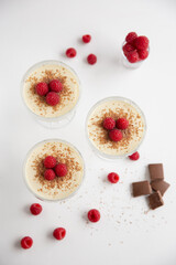 Overhead closeup view of crystal cups with vanilla flavoured panna cotta with fresh raspberries and...