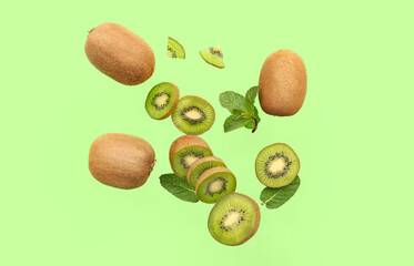 Flying cut kiwi and mint leaves on green background