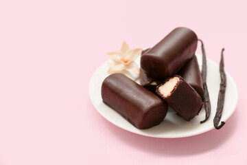 Plate with tasty chocolate glazed curd snacks with vanilla flavor on pink background
